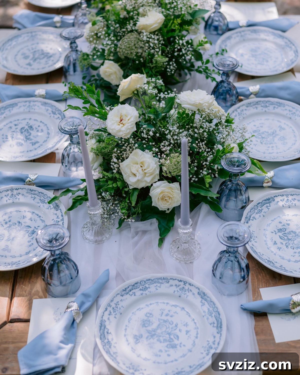 Elegant table setting with soft blue floral patterned plates, blue linen napkins, and tinted wine glasses for a sophisticated wedding.