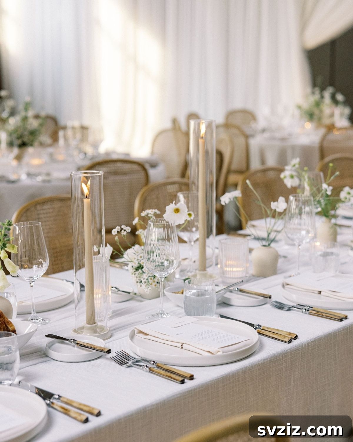 Elegant white and champagne wedding reception table setting with candles and natural wood accents.