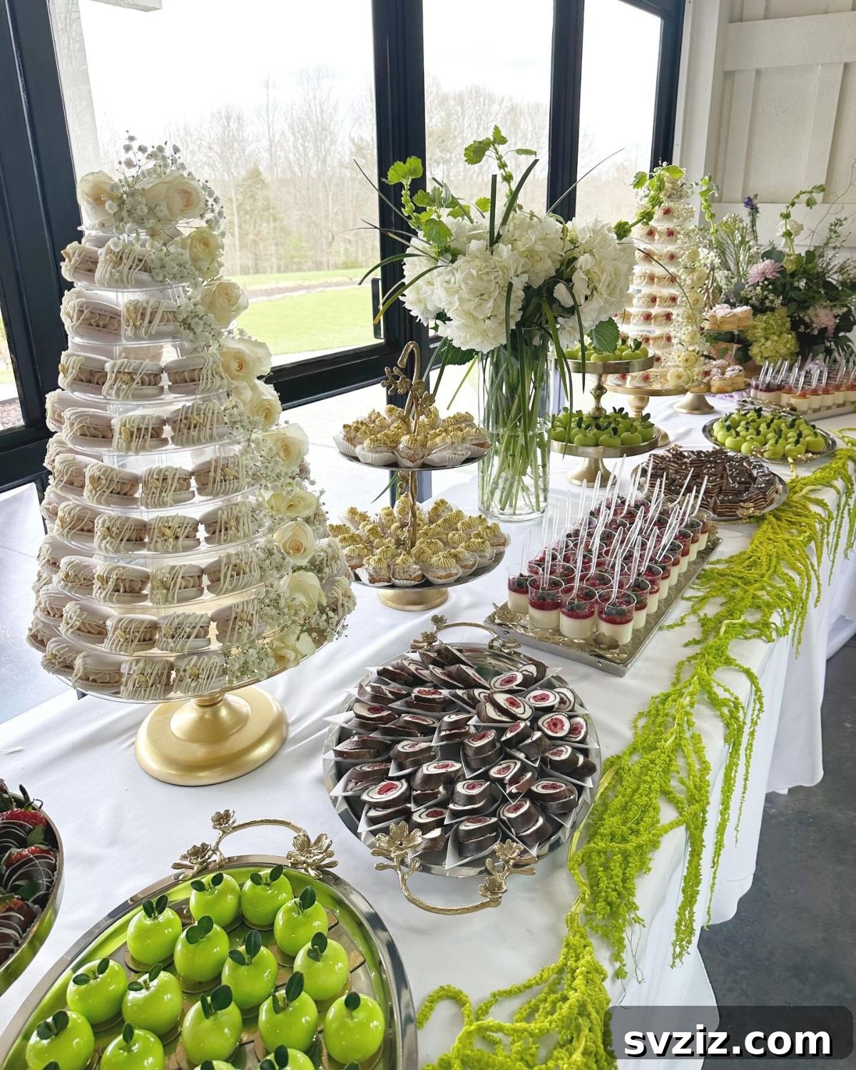 Exquisite Wedding Dessert Spreads 5 An elaborate garden-inspired luxe dessert table, featuring a lavish display of pastries, macarons, and shooters, adorned with fresh greenery and white hydrangeas.