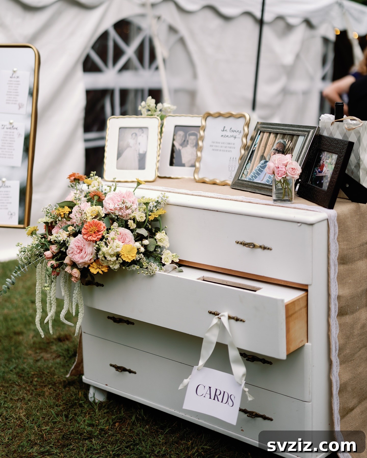 Elegant dresser used as a wedding memory table with framed photos and flowers.
