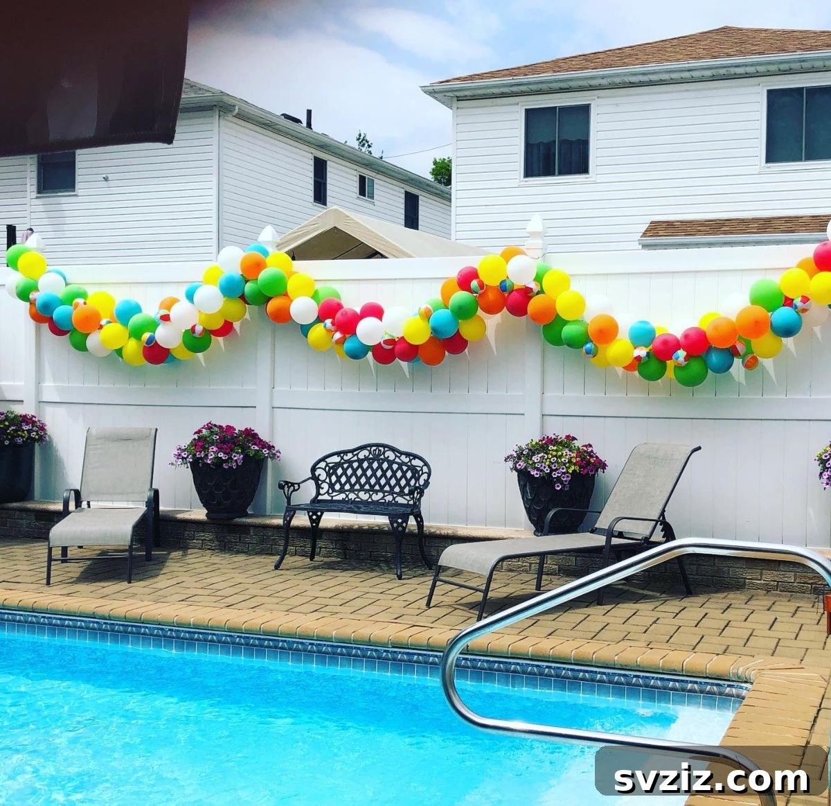 Colorful balloon garland draped along a pool fence for an elevated party decoration.