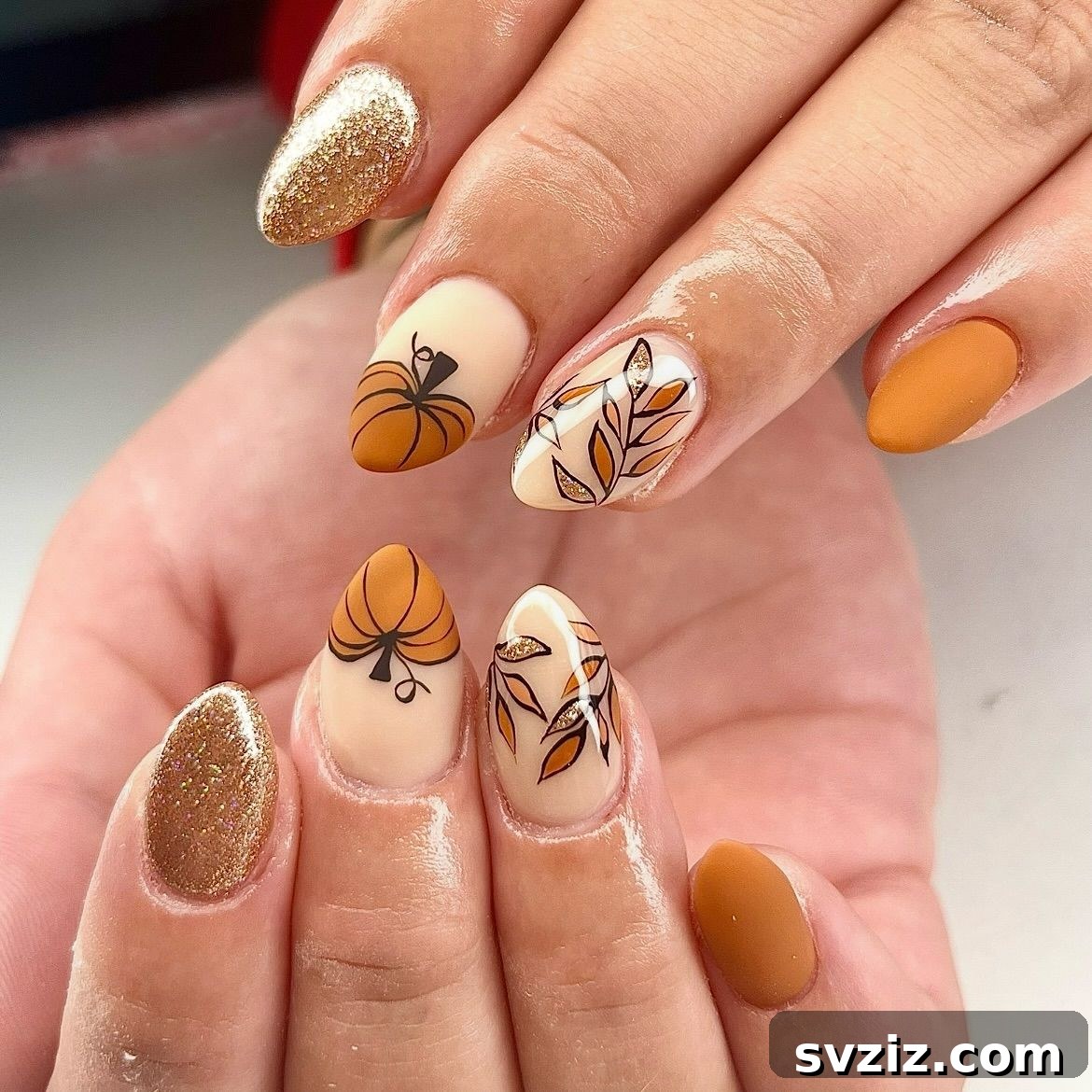 Chic Autumn Almond Nail Ideas 13 Whimsical almond nails featuring an elegantly designed pumpkin accent and shimmering gold polish for fall festivities