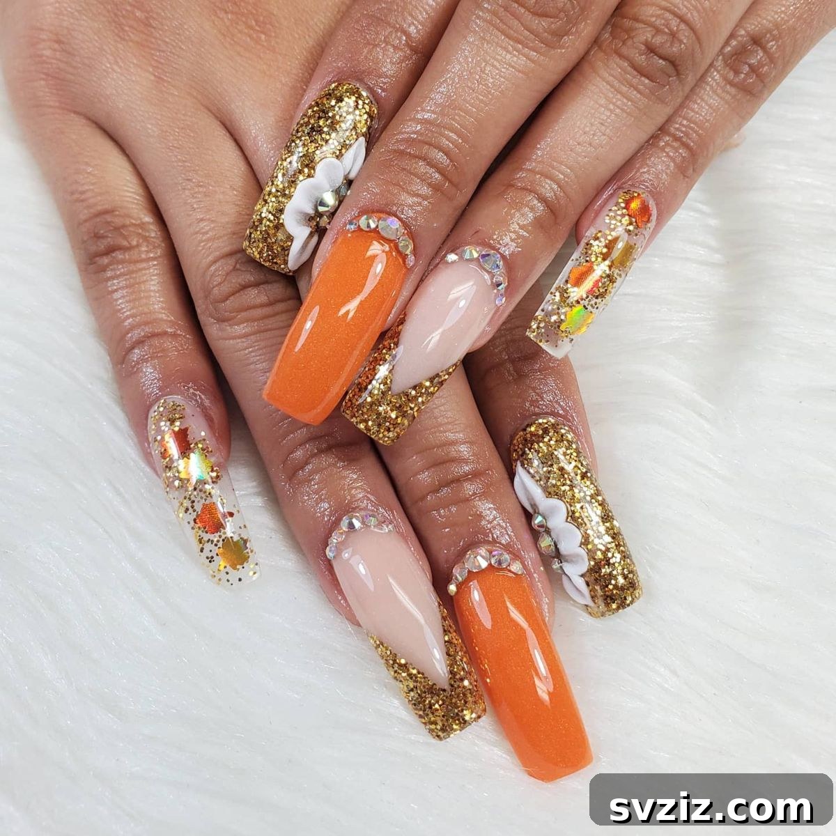 Stunning Thanksgiving Acrylic Nail Art for the Holiday Season 23 Super celebratory gold and orange Thanksgiving acrylic nails with glitzy gold, bold white flowers, leaves, and sparkly orange accents.