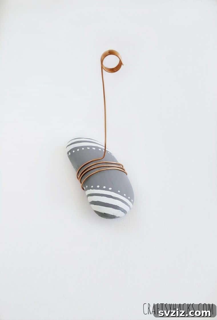 Curled wire extending from a painted rock, ready to hold a photo