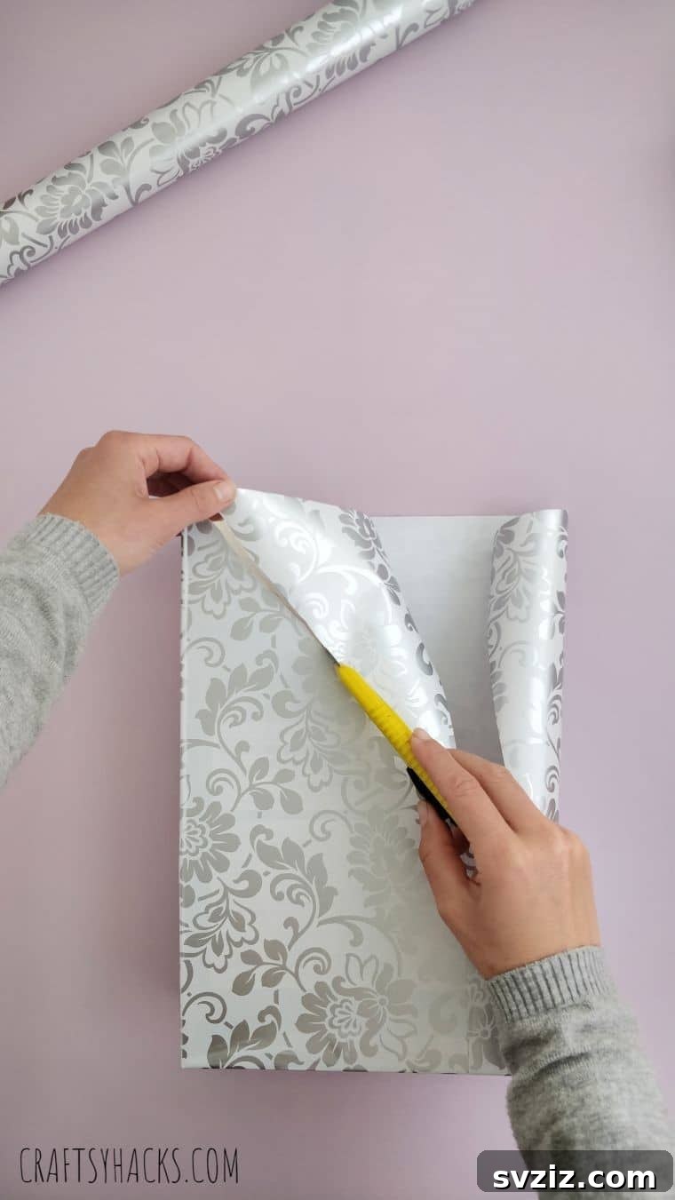 Trimming decorative paper along the edges of the DIY magazine holder for a clean, professional finish