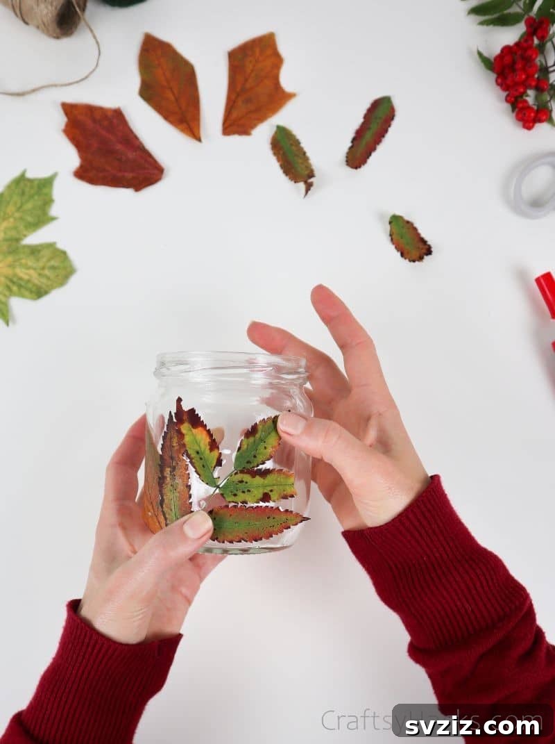 A hand firmly pressing down on multiple layered leaves attached to the jar, ensuring they adhere well to the curved surface.