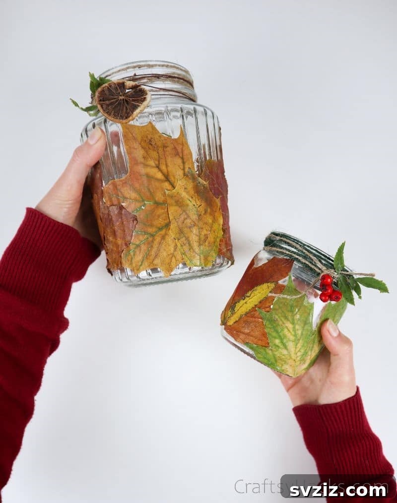 A pair of hands proudly holding up two newly completed DIY leaf candle holders, ready for display.