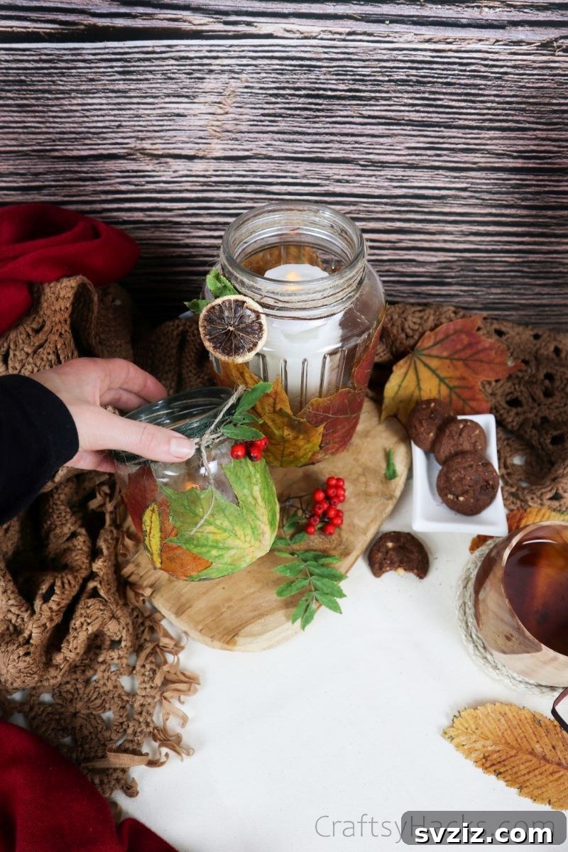A cozy fall display featuring multiple DIY leaf candle holders alongside pumpkins and other autumnal elements.