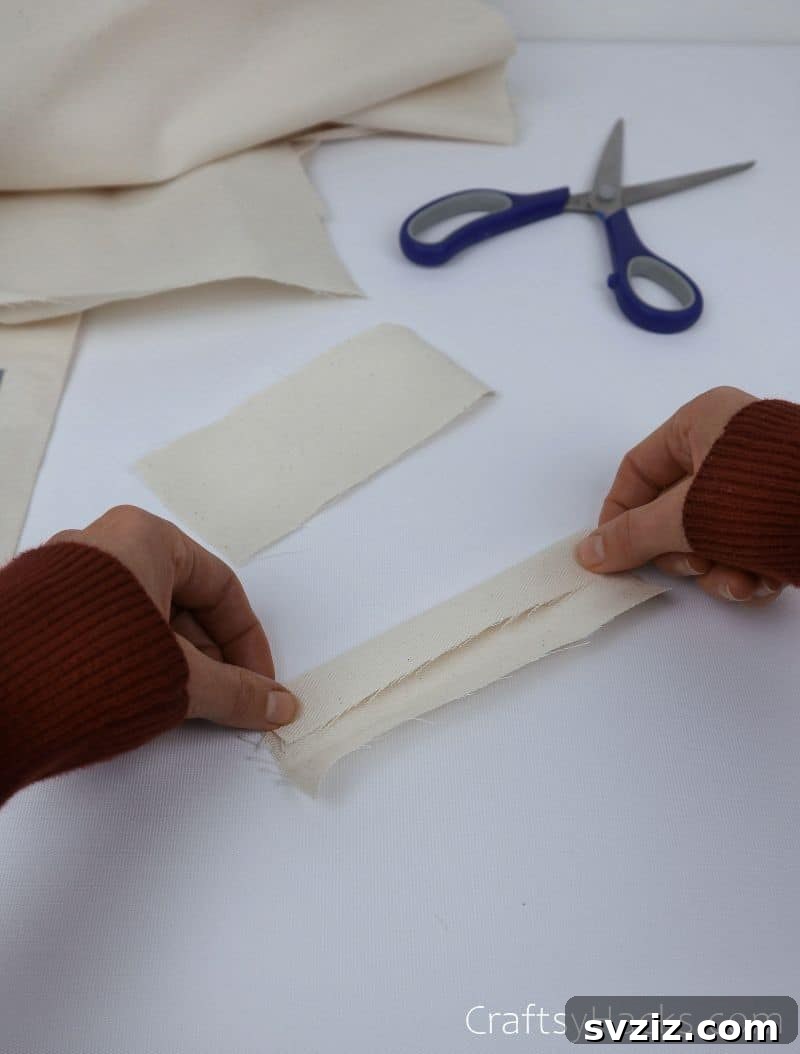 Folding a fabric piece inward to prepare a hanging loop