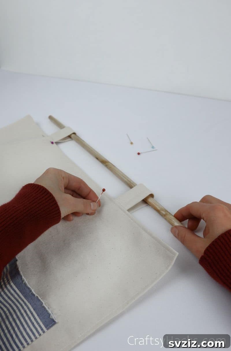 Pinning the fabric straps to the top of the organizer around a wooden dowel