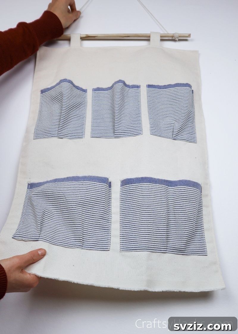 A completed DIY hanging organizer with various pockets, ready for decoration