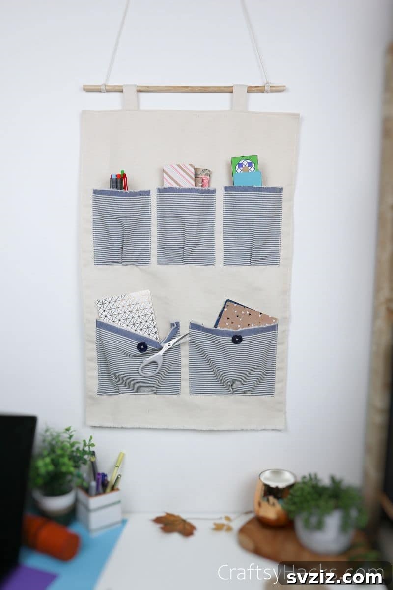 DIY pocket organizer filled with craft supplies and stationery, hanging on a wall