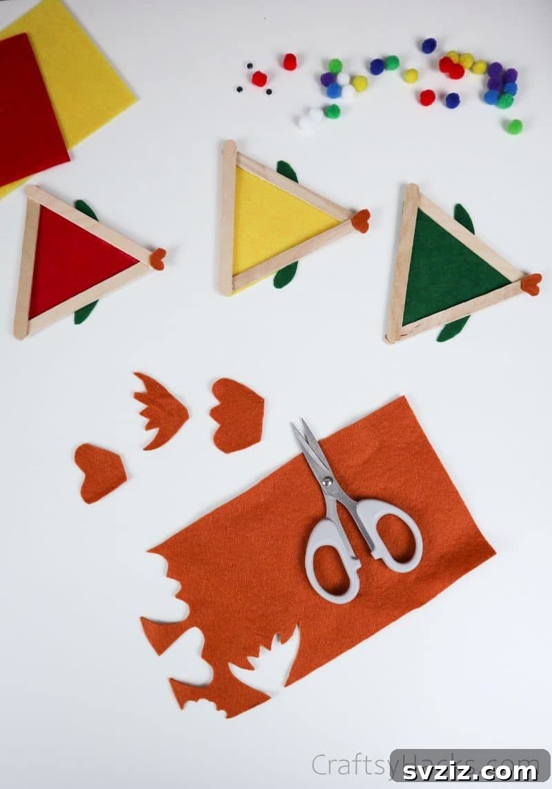 Simple Fish Crafts Kids Love to Make at School 12 Hands cutting various tail shapes from an orange felt sheet.