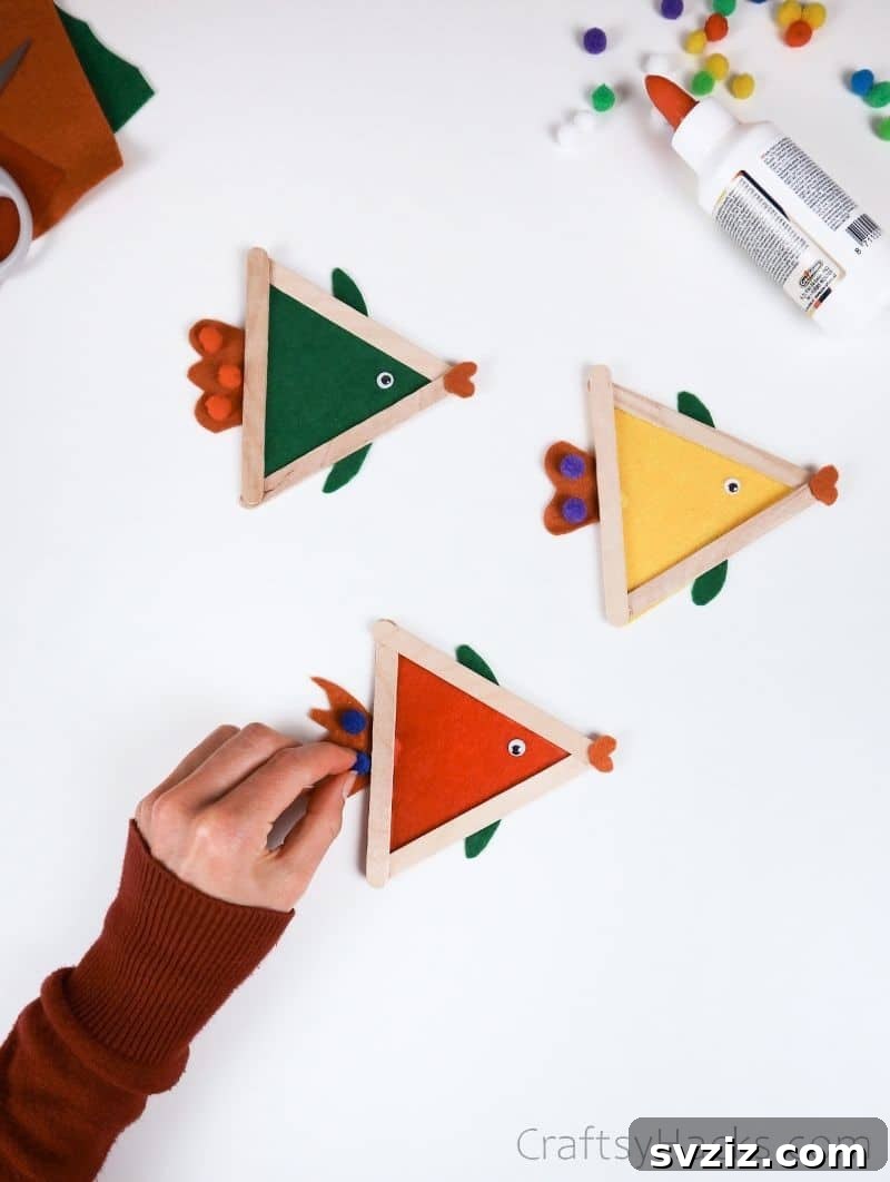 Simple Fish Crafts Kids Love to Make at School 14 Adding colorful pom-poms to the completed fish crafts as decoration.