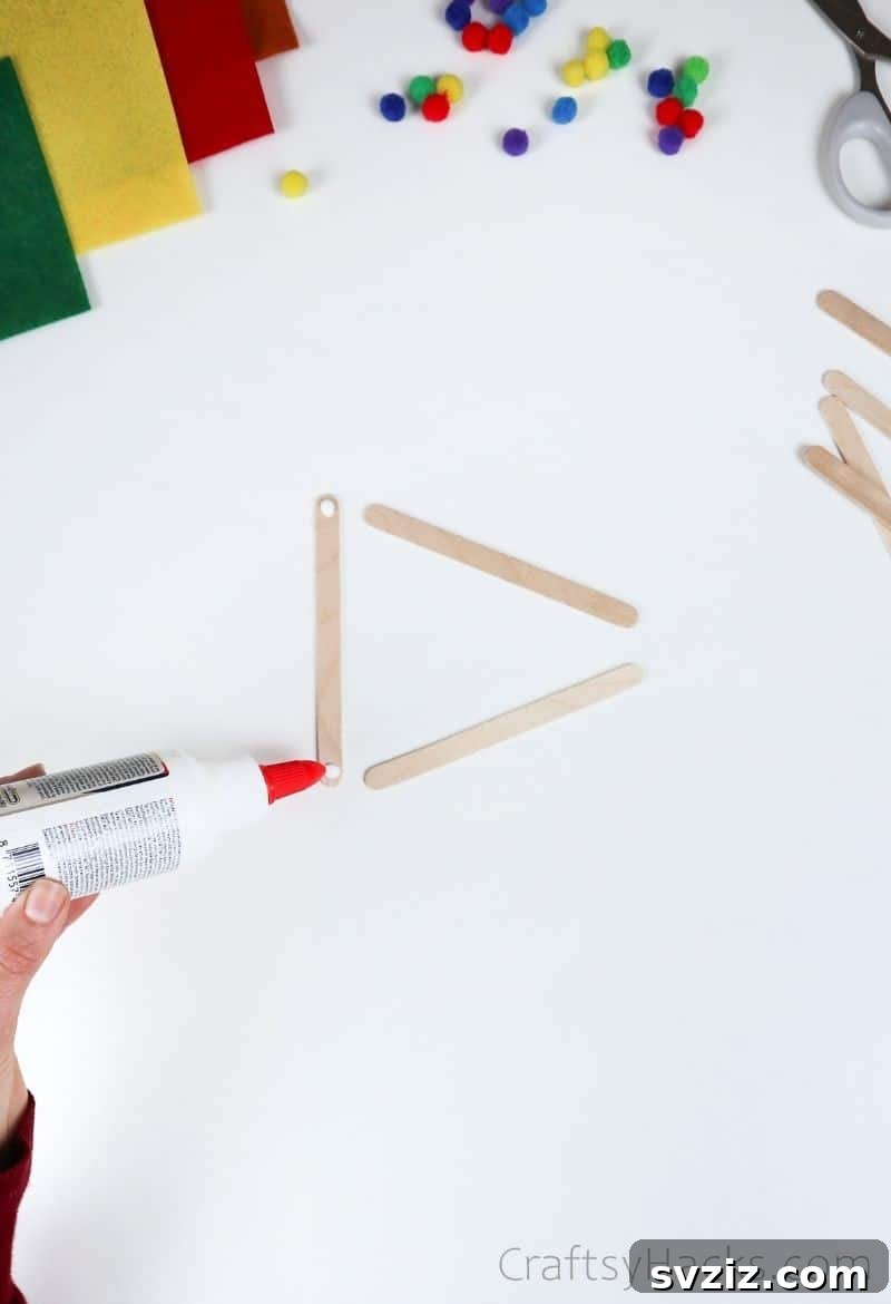 Simple Fish Crafts Kids Love to Make at School 6 Close-up of hands applying glue to popsicle sticks to form a triangle.