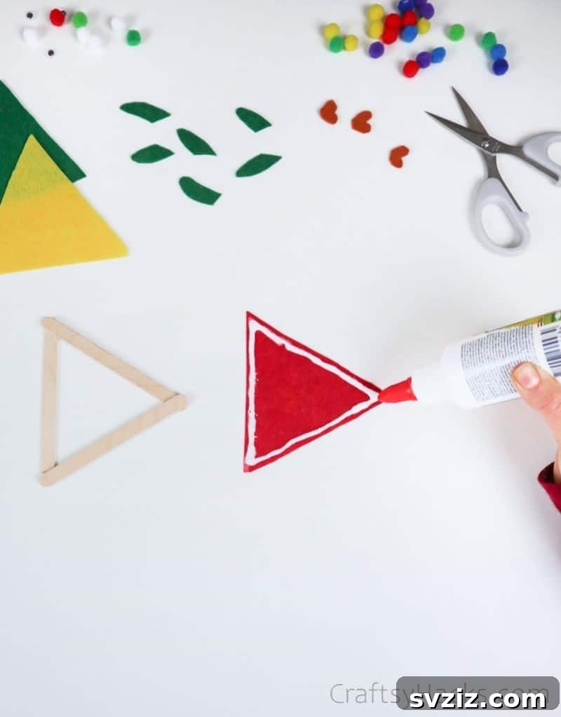 Simple Fish Crafts Kids Love to Make at School 8 A felt triangle being glued onto the popsicle stick frame.