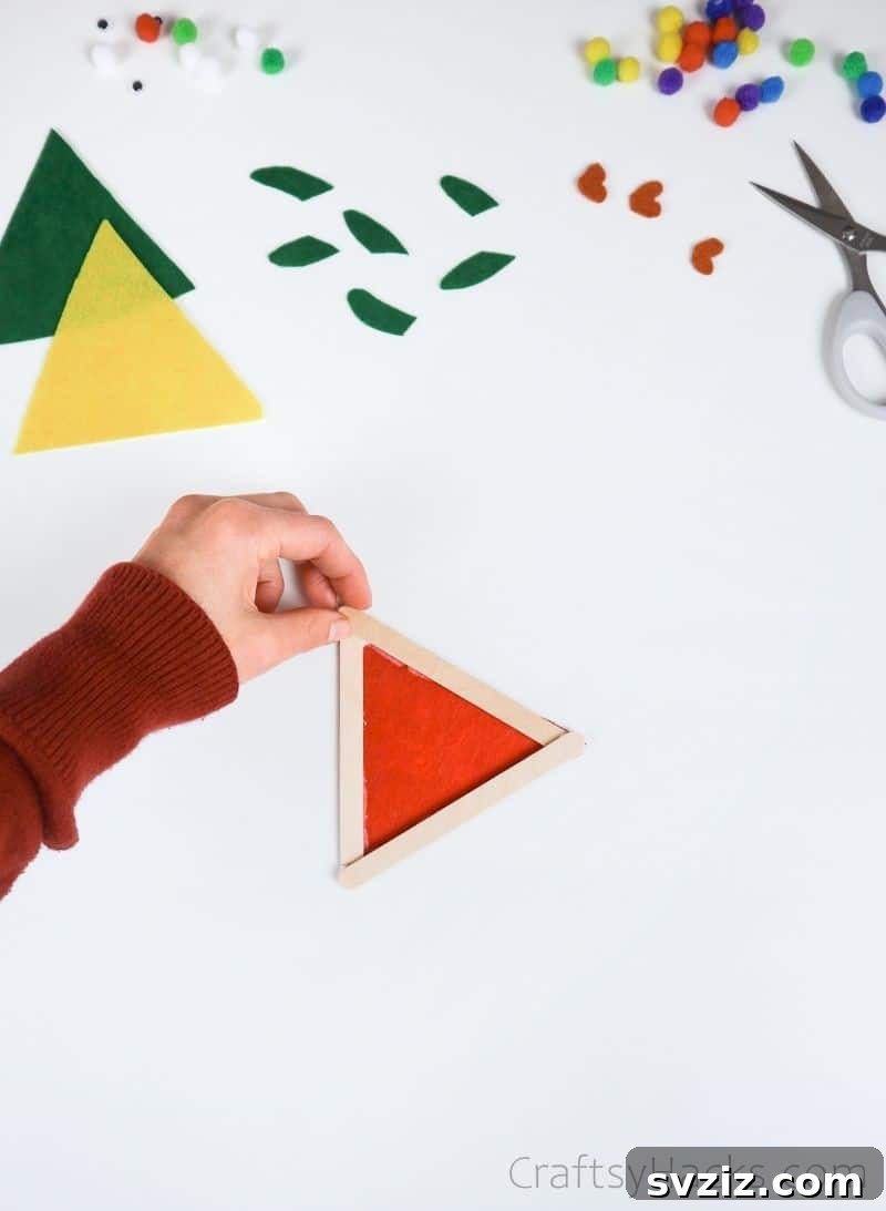 Simple Fish Crafts Kids Love to Make at School 9 The felt body now securely glued onto the popsicle stick triangle, forming the basic fish shape.