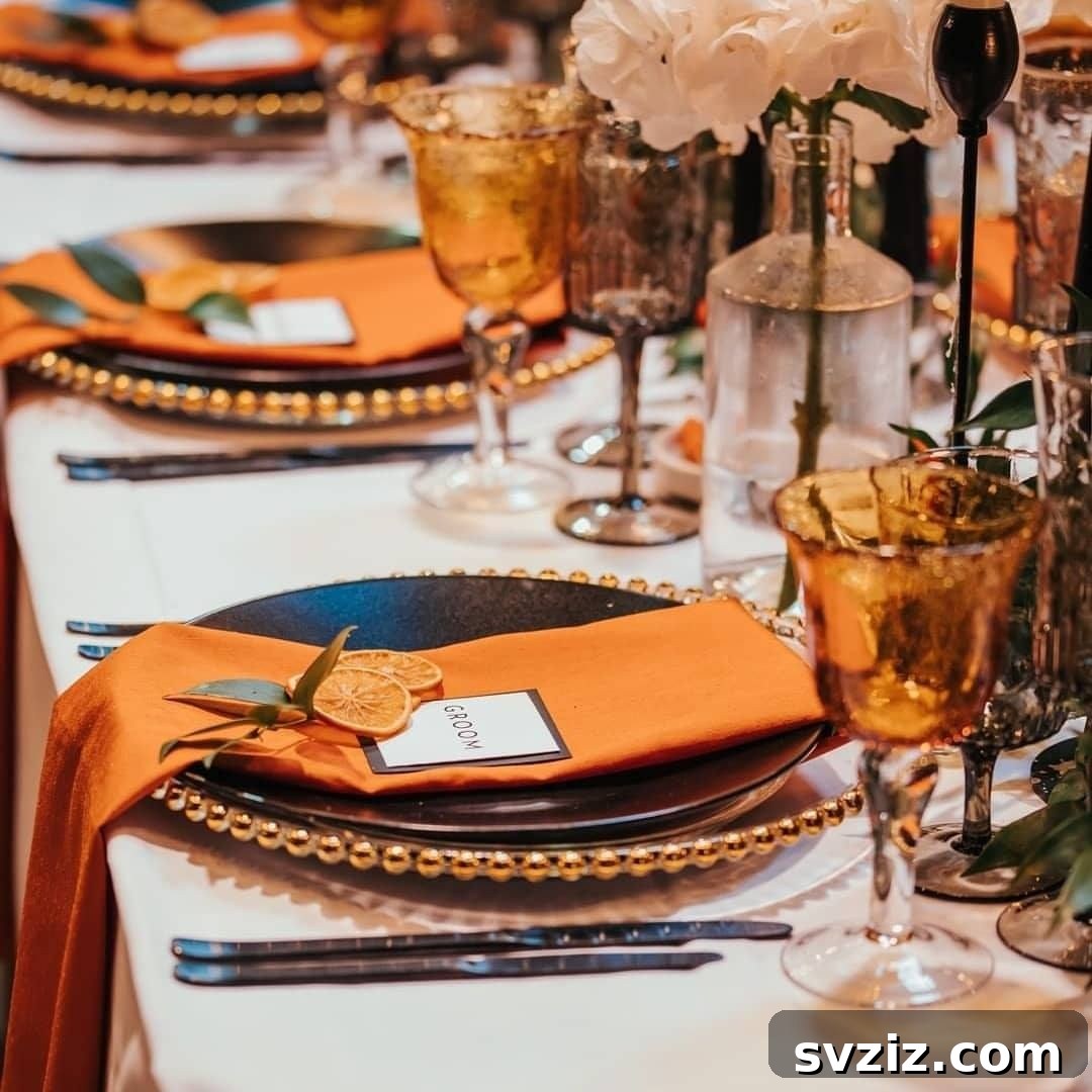 Vibrant wedding table decor with orange accents, gold, ebony, and unique seating cards.
