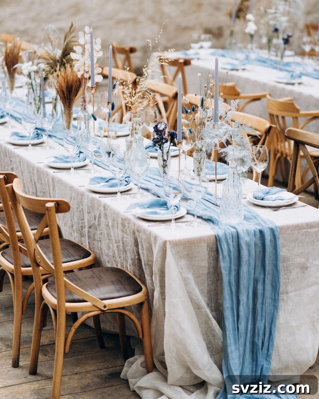 Beach-themed wedding table with a blue table runner, lavender sprigs, and blue taper candles overlooking the ocean.