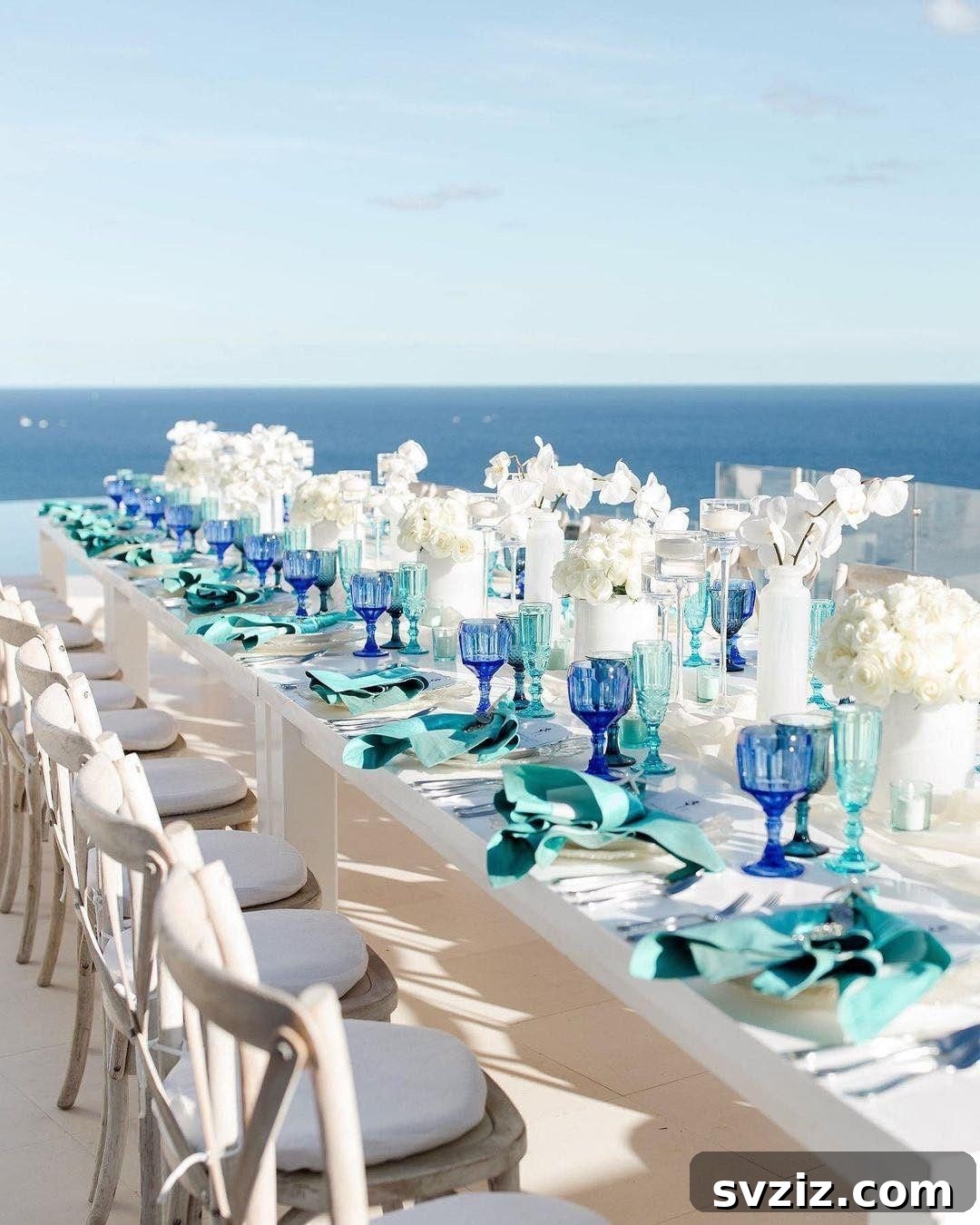 Wedding table with vintage glassware and silverware, beautifully framed by a violet-blue ocean backdrop.