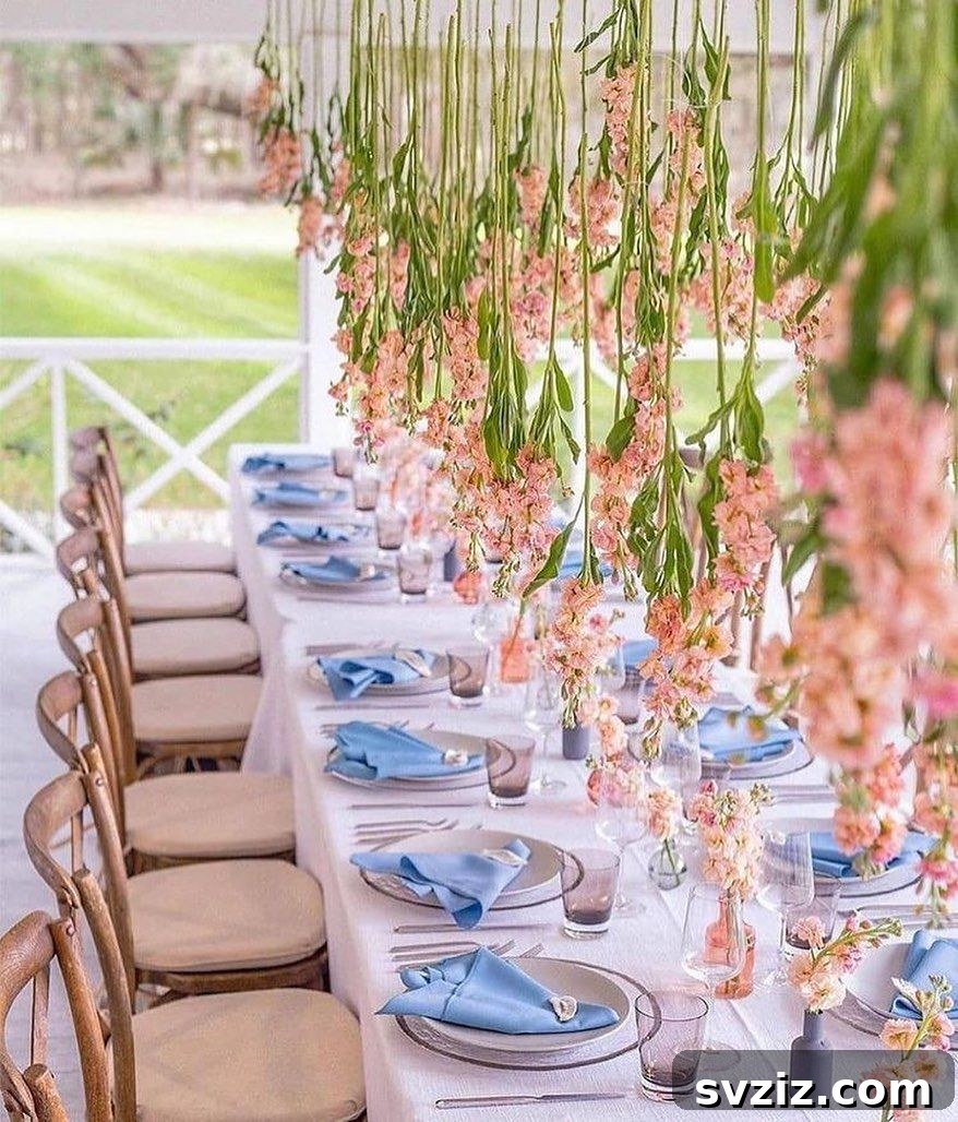 Wedding table with stunning hanging coral orchids as centerpieces, complemented by lavender-blue napkins and bruised lavender glassware.