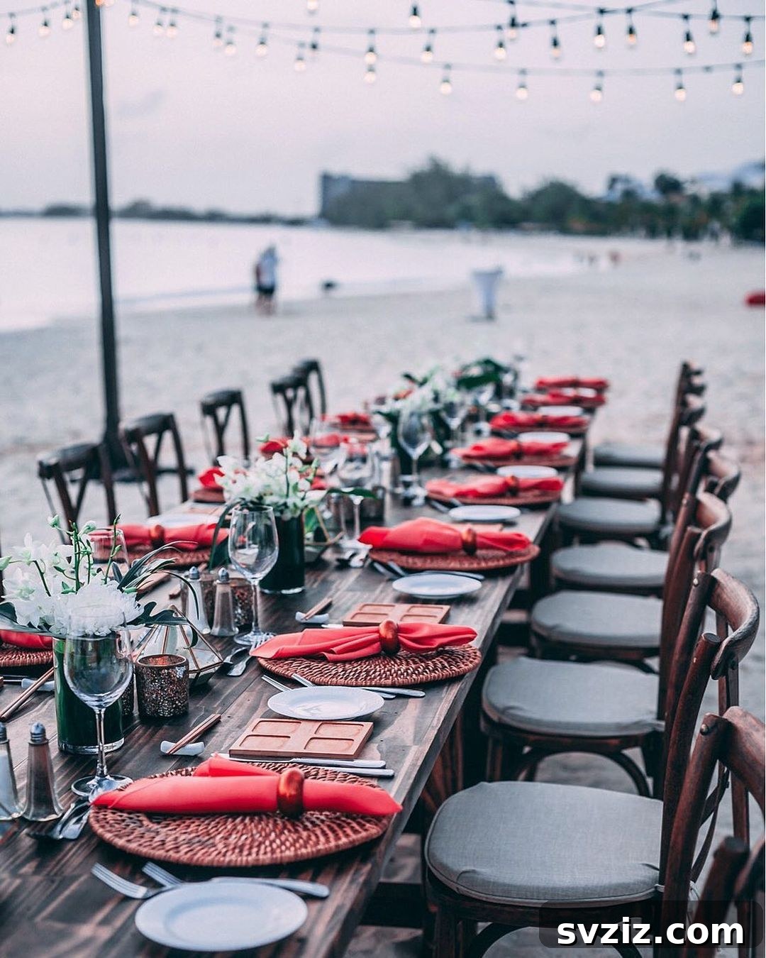 Romantic outdoor wedding table with vibrant red napkins under the setting sun.