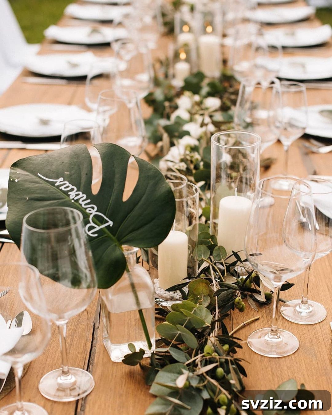Tropical wedding table with a single palm leaf centerpiece and olive leaf runner.